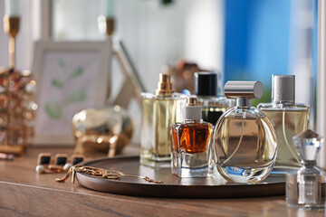 Bottles of different perfumes and accessories on wooden table, closeup