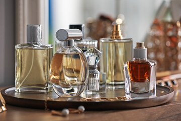 Bottles of different perfumes and accessories on wooden table, closeup