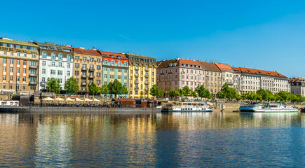 A view from the Vltava river towards colourful buildings on the east bank in Prague in springtime