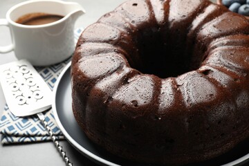 Tasty chocolate bundt cake and server on grey table, closeup