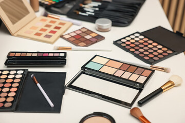 Different makeup products and brushes on dressing table, closeup