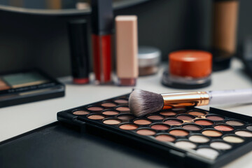 Different makeup products and brush on dressing table indoors, closeup