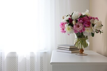 Bouquet of beautiful peonies and books on white table indoors, space for text. Interior design