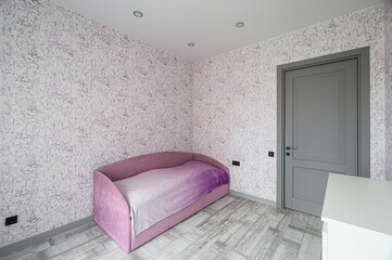 serene room with patterned wallpaper, a pink bed, grey door, and light wood-look flooring