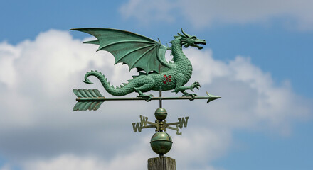 Weather vane featuring a green dragon against a cloudy blue sky