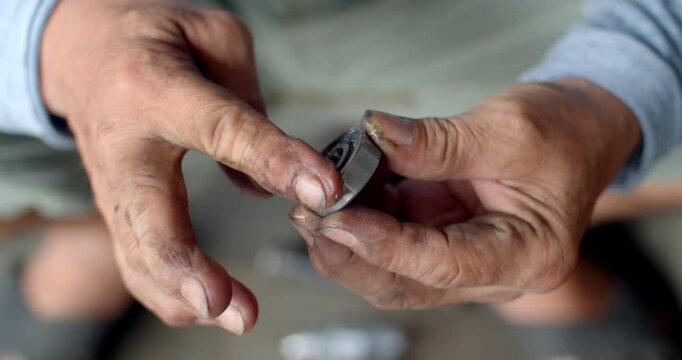 Applying thick grease to a new ball bearing before inserting it into the hub of a motorcycle wheel, preparing for smooth operation.