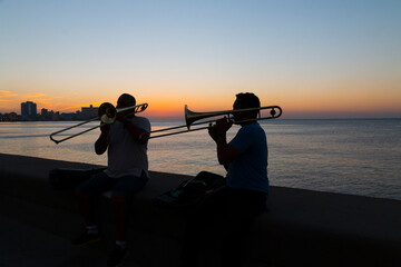 Cuba, Havana. Trombone players in silhouette against Havana's harbor from the rocks along the Malecon. © Danita Delimont