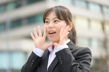 手を顔の横で大きく広げて声を出すような仕草を見せる新入社員