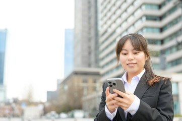 スマートフォンを見つめながら親しげな笑みを浮かべる新入社員
