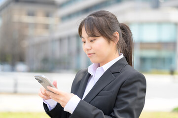 スマートフォンを真剣に見つめながら操作するフレッシャーズの女性