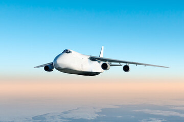 White wide body transport freight aircraft fly in the air above the clouds