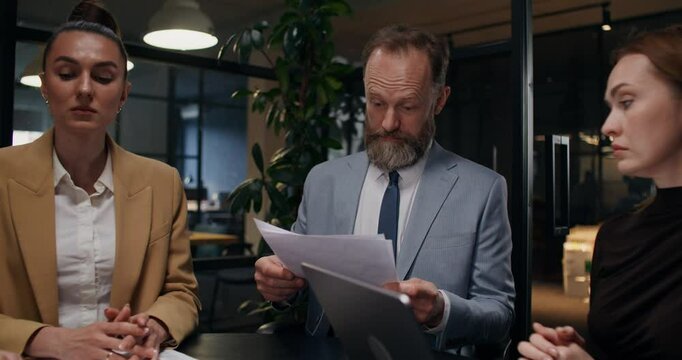 The boss shouts at his colleagues during a meeting in the office. He tears up the documents and throws the papers up