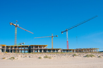 Construction cranes at building site on a coast lina © unclepodger