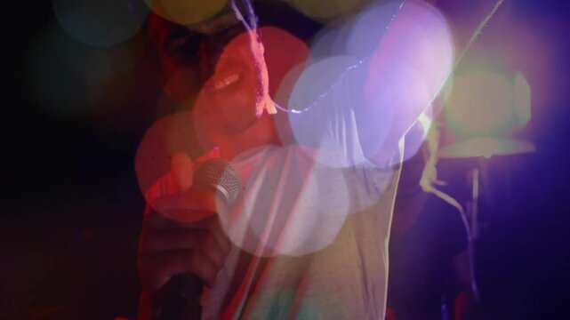Bokeh overlay revealing singer gripping mic stand singing with keyboardist silhouetted for concert