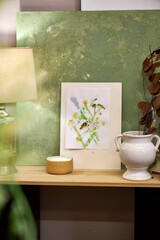 Finished botanical print displayed in cozy interior. Handmade floral artwork with wildflowers on shelf with natural home decor elements