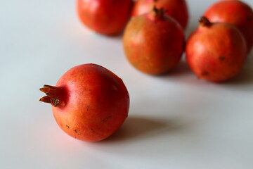 Pomegranate. Fresh fruits on a white surface, highlighted in soft light