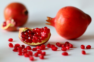 Pomegranate. Open fruit with glistening ruby red arils on a white surface, captured in soft natural light