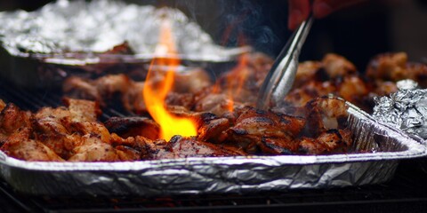 Juicy grilled meat sizzling over flames, ready to be served at a barbecue.