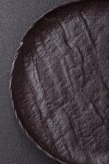 Empty round black plate for food, risotto or pasta. Empty plate on dark background