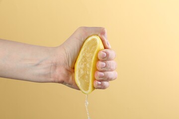 Woman squeezing lemon on yellow background, closeup