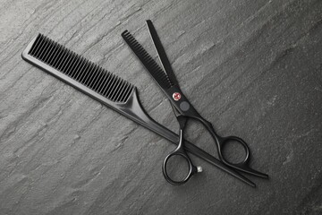Comb and scissors on black table, flat lay. Hairdresser's tools