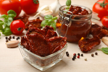 Tasty sun dried tomatoes, fresh vegetables and peppercorns on light wooden table, closeup