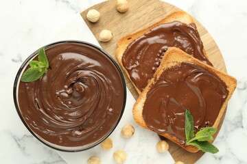 Tasty chocolate spread with mint and hazelnuts on white marble table, top view