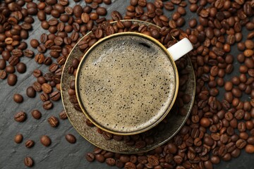 Aromatic coffee in cup and beans on black table, flat lay
