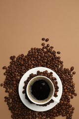 Aromatic coffee in cup and beans on beige background, flat lay. Space for text