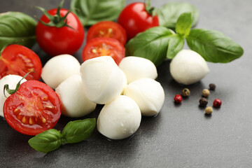 Mozzarella cheese, tomatoes, basil and peppercorns on grey table, closeup