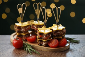 Tasty canapes with cheese on wooden table against blurred lights, closeup. Bokeh effect