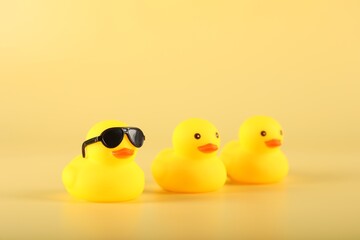 Three cute rubber ducks on yellow background, closeup
