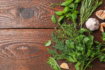 Different fresh herbs and spices on wooden table, flat lay. Space for text