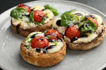 Tasty stuffed mushrooms served on black table, closeup