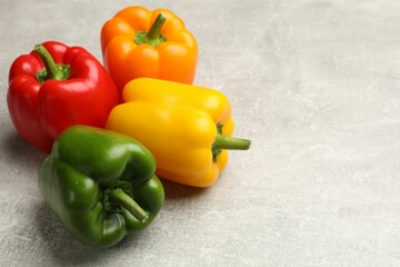 Fresh colorful bell peppers on gray textured table, closeup. Space for text