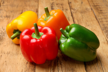 Fresh colorful bell peppers on wooden table, closeup