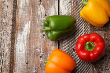 Fresh colorful bell peppers on wooden table, flat lay. Space for text