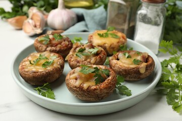 Tasty stuffed mushrooms and spices on white marble table, closeup