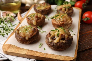 Delicious stuffed mushrooms with melted cheese and thyme on wooden table, closeup