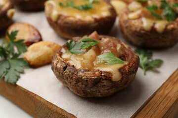 Delicious stuffed mushrooms with melted cheese and parsley on white table, closeup
