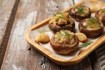 Delicious stuffed mushrooms with melted cheese, garlic and dill on color wooden table, closeup