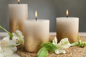 Burning candles and lily flowers on white table, closeup
