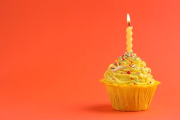 Burning candle in cupcake on orange background, space for text