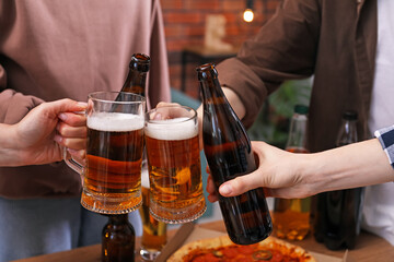 Friends clinking glasses of beer indoors, closeup