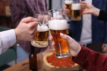Friends clinking glasses of beer at table, closeup