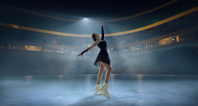 Figure skater woman skating on ice stadium.