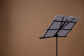 Stand with music sheets on dark beige background, space for text