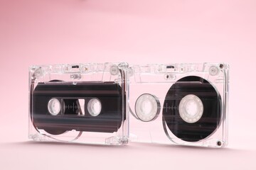 Audio cassettes with magnetic tapes on pink background, closeup