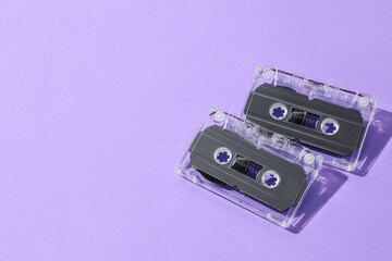 Audio cassettes with magnetic tapes on violet background, flat lay. Space for text