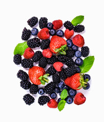 Assortment of fresh ripe berries including strawberries, raspberries, blueberries and blackberries scattered with mint leaves. White isolated background for packaging or healthy food design.